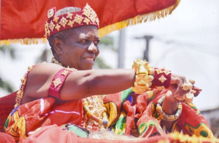 Felicity Apaah Nana Kow Ackon V, dressed in her chiefly regalia during the 2018 Fetu Afehye Festival in Cape Coast, represents a unique figure—a woman occupying a traditionally male stool. In keeping with custom, she is dressed in male attire. As a senior divisional chief, she rides in her palanquin and dances while exchanging pleasantries with her constituents. Photo by Felicity Apaah.