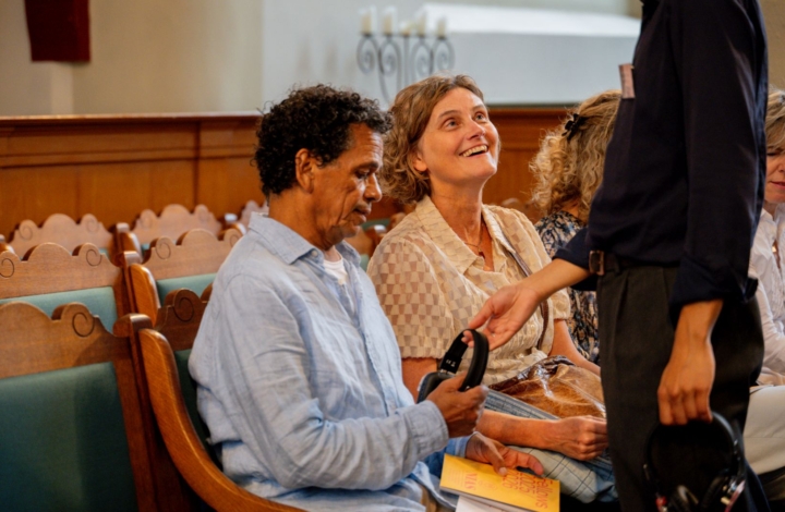 Photo of a NIAS employee who hands a visitor a pair of headphones before the start of an event.